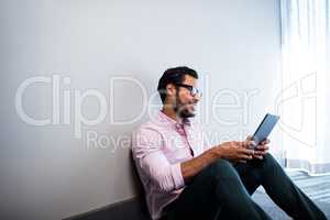 Smiling businessman using tablet computer while sitting on the f