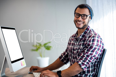 Smiling hipster working at computer desk