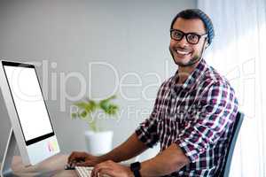 Smiling hipster working at computer desk