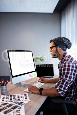 Serious hipster working at computer desk