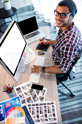 Attractive hipster smiling at camera while working at desk