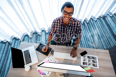 Attractive hipster smiling at camera while working at desk