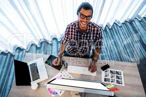 Attractive hipster smiling at camera while working at desk