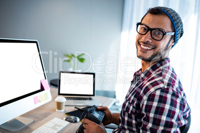 Attractive hipster smiling at camera while working at desk