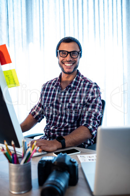 Portrait of hipster photographer smiling at camera while sitting