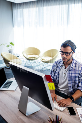 An hipster man working at computer desk