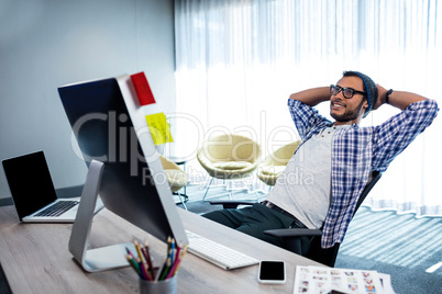Smiling casual man with hands behind hand resting at desk