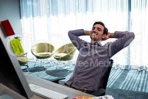 Smiling casual man with hands behind hand resting at desk