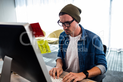 Portrait of serious hipster man working at computer desk