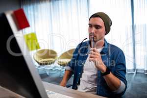 Hipster man holding glasses while working at computer desk