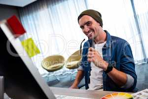 Hipster man holding glasses while working at computer desk