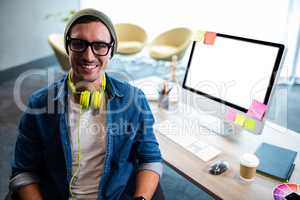 Smiling hipster businessman posing for camera while sitting at d