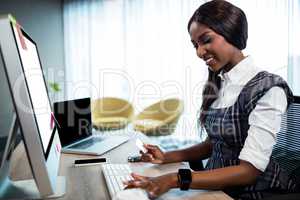 Business woman holding credit card and typing on the computer
