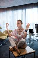 Businesswoman doing yoga with hands in the air