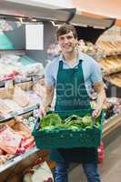 Portrait of man grocer holding a crate of vegetables