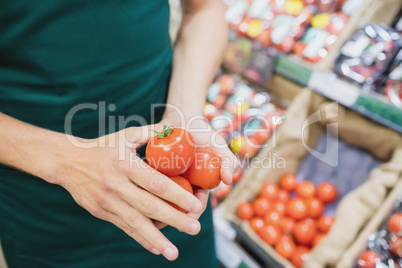 Focus on foreground of man grocer holding tomatoes