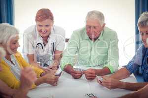 Pensioners playing cards with nurse