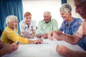Pensioners playing cards with nurse