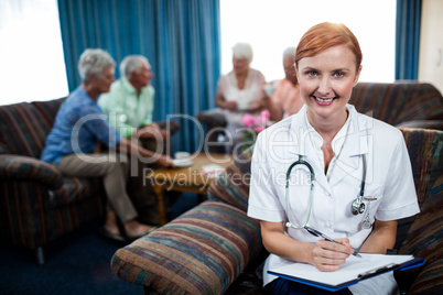 Portrait of a nurse with pensioners in background