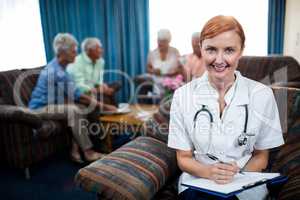 Portrait of a nurse with pensioners in background