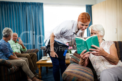 Senior woman reading book with nurse