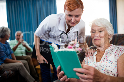 Senior woman reading book with nurse