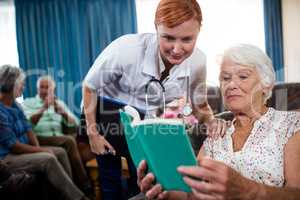 Senior woman reading book with nurse