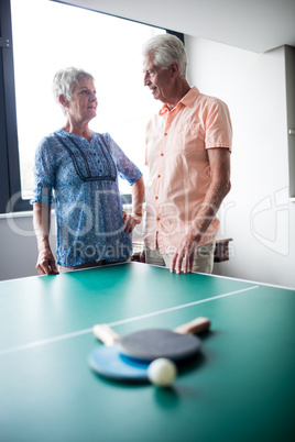 Couple of seniors interacting behind a ping pong table
