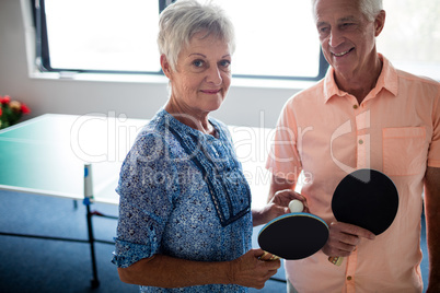 Portrait of a couple of seniors front of a ping pong table