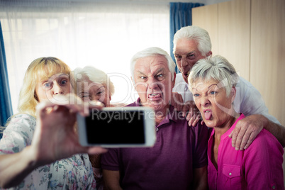 Group of seniors doing a selfie with a smartphone and funny face