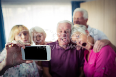 Group of seniors doing a selfie with a smartphone and funny face