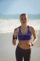 Beautiful woman jogging on a beach and listen music