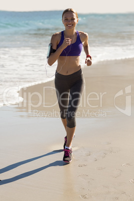 Beautiful woman jogging on a beach and listen music