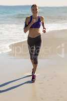 Beautiful woman jogging on a beach and listen music