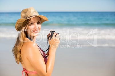 Attractive woman in bikini taking photographs