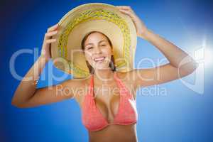 Attractive woman wearing bikini and hat posing against sky