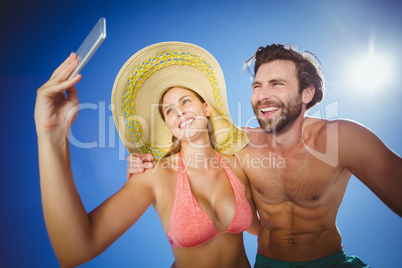 Couple taking selfie against blue sky