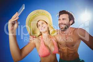 Couple taking selfie against blue sky