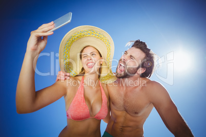 Couple taking selfie against blue sky