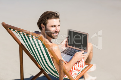 Man sitting on armchair at beach