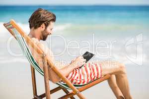 Man sitting on armchair at beach