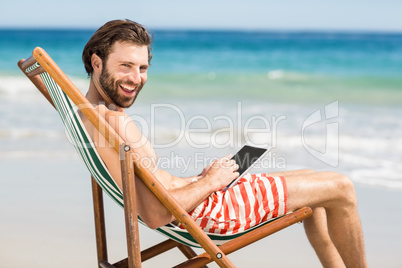 Man sitting on armchair at beach