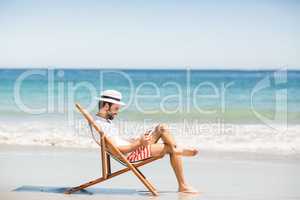 Man sitting on armchair at beach