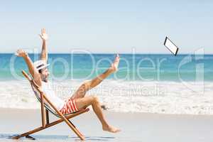 Man throwing digital tablet on beach