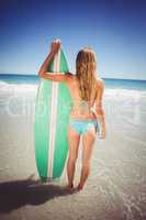 Woman standing with surfboard on beach