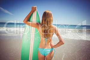 Woman standing with surfboard on beach