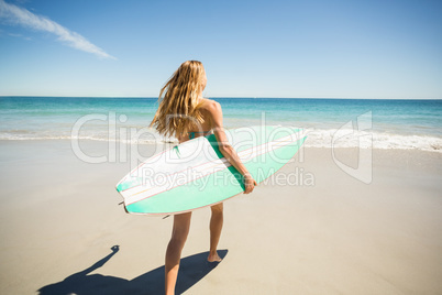 Woman walking with surfboard on beach