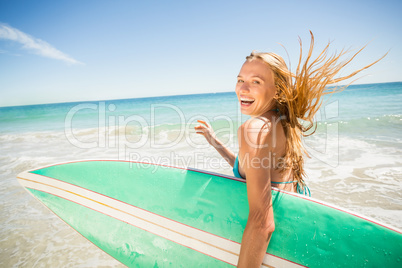 Woman running with surfboard on beach