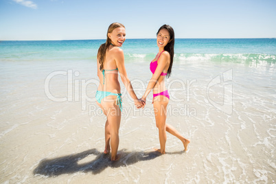 Female friends holding hands on beach