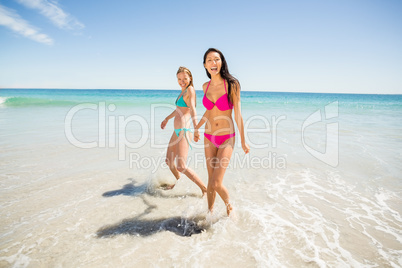 Female friends holding hands on beach